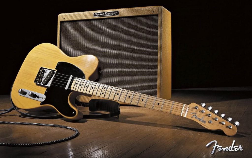 Một cây đàn guitar điện màu đen được kết nối với amply