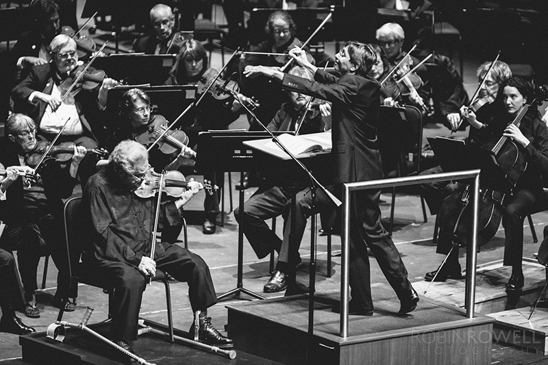 Một nghệ sĩ độc tấu violin đang biểu diễn trên sân khấu, ánh đèn tập trung vào nhạc cụ và đôi tay điêu luyện